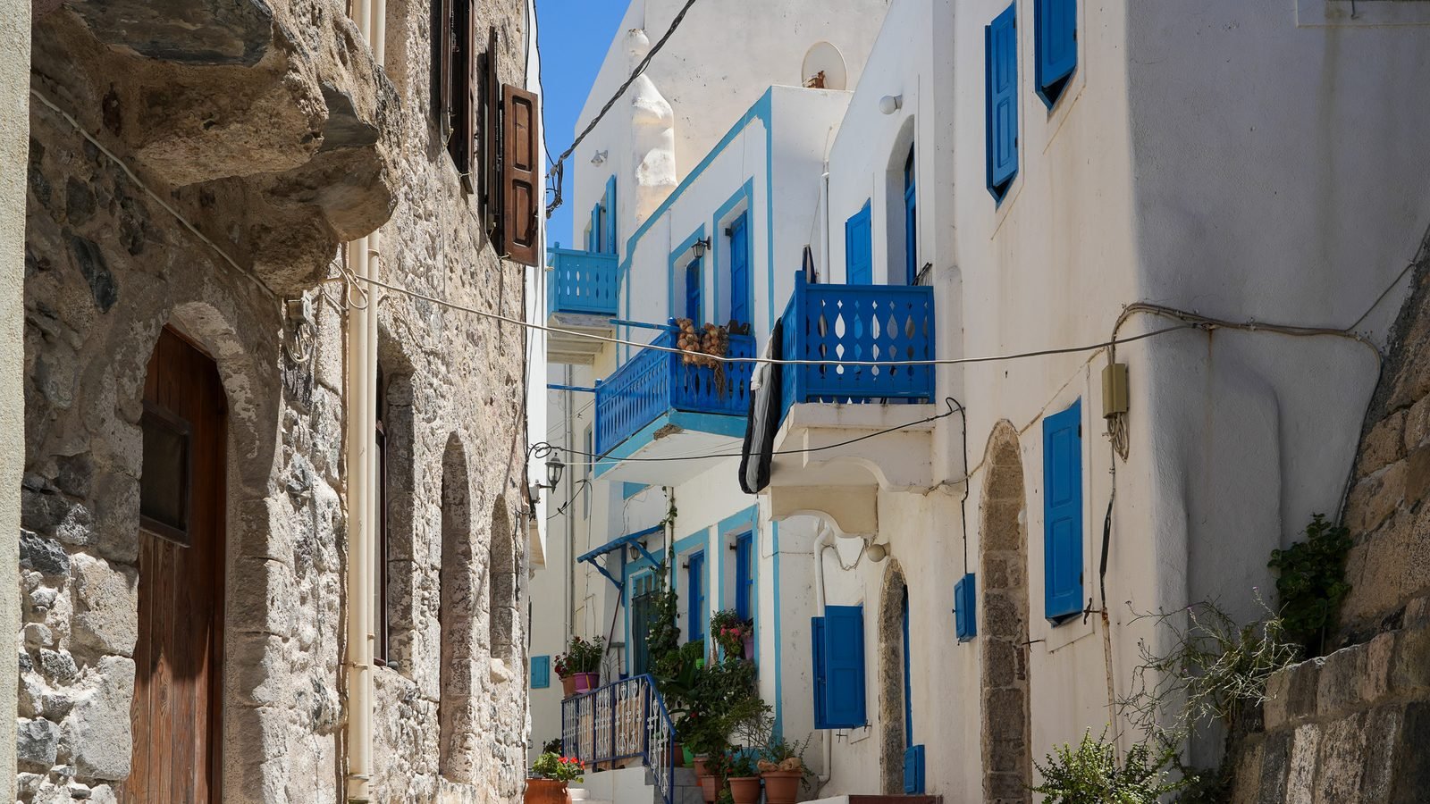 A narrow whitewashed lane with blue shutters and stone steps